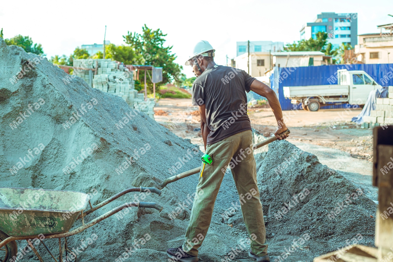 chef maçon  sur un chantier prenant du sable gravier avec une pèle