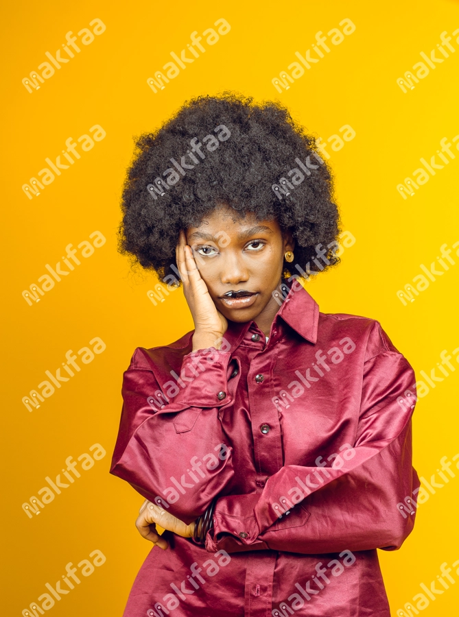 Femme afro pensive avec une main sur sa joue