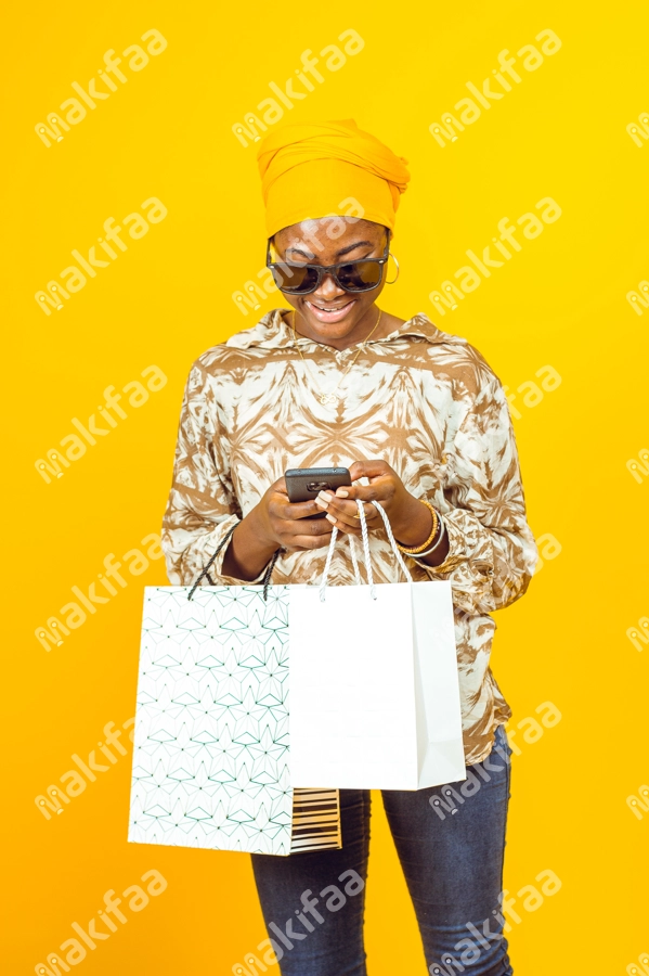 Femme avec des lunettes de soleil, un téléphone et des sacs de shopping