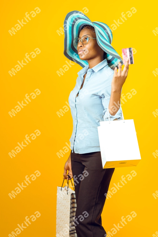 Femme avec des sacs de shopping, un chapeau et une carte de crédit