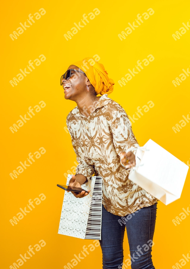 Femme avec éclat de rire, un téléphone et des sacs de shoppings