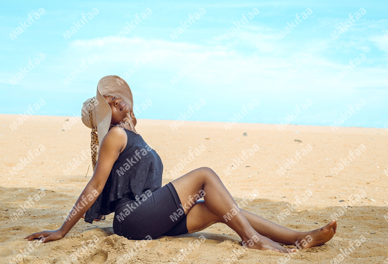 Femme en bordure de plage avec un chapeau de soleil