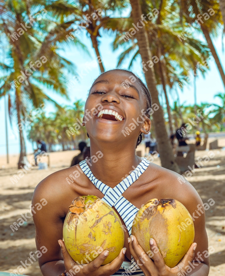 femme en joie tenant des noix de coco à la plage