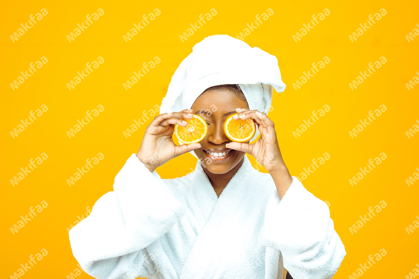 femme en peignoir blanc posant des oranges sur les yeux
