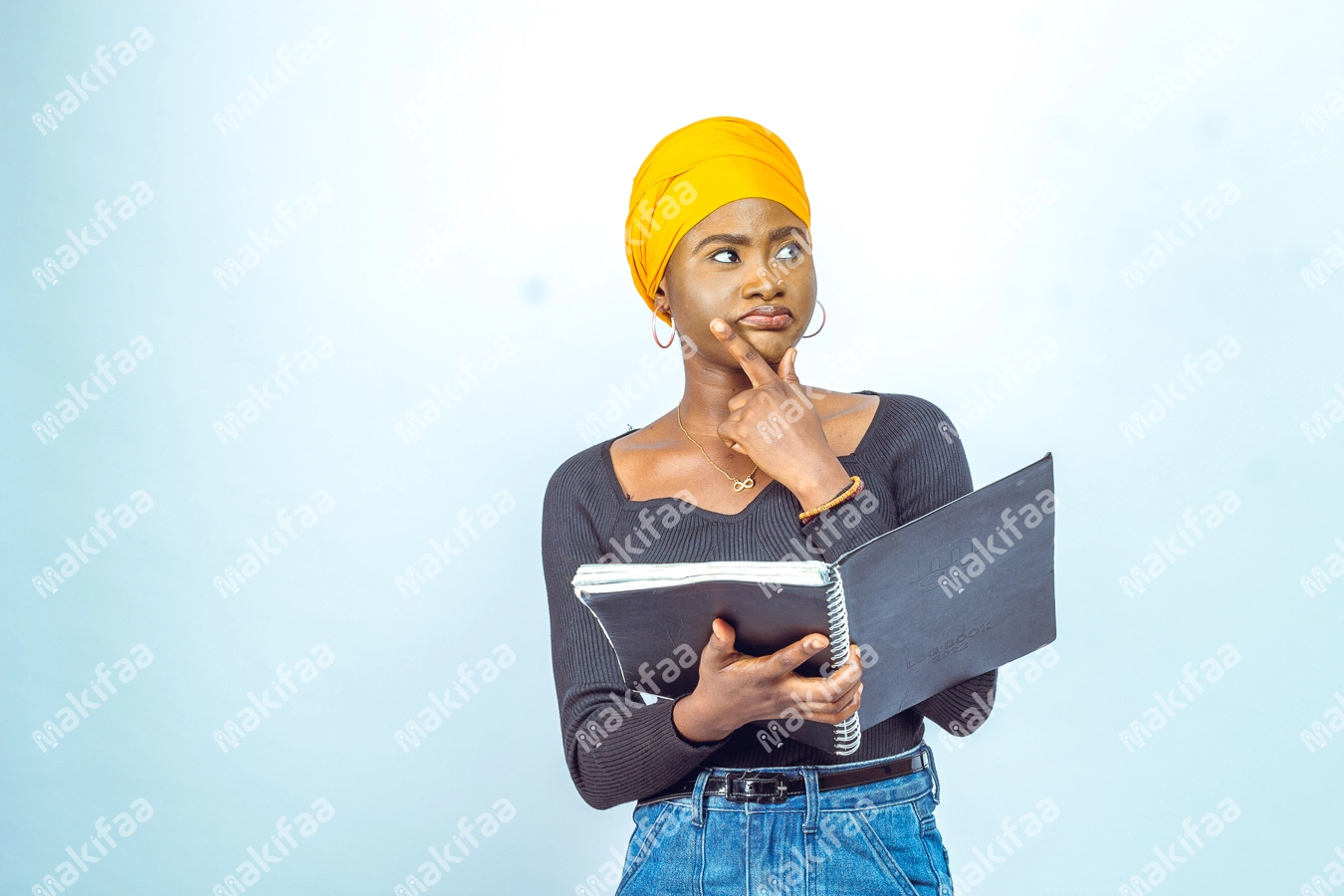 Femme étudiante pensive devant son cahier avec un doigt sur le menton