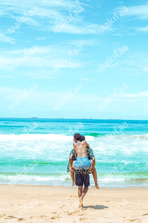 homme portant sa femme au dos  contemplant les vagues de la mer