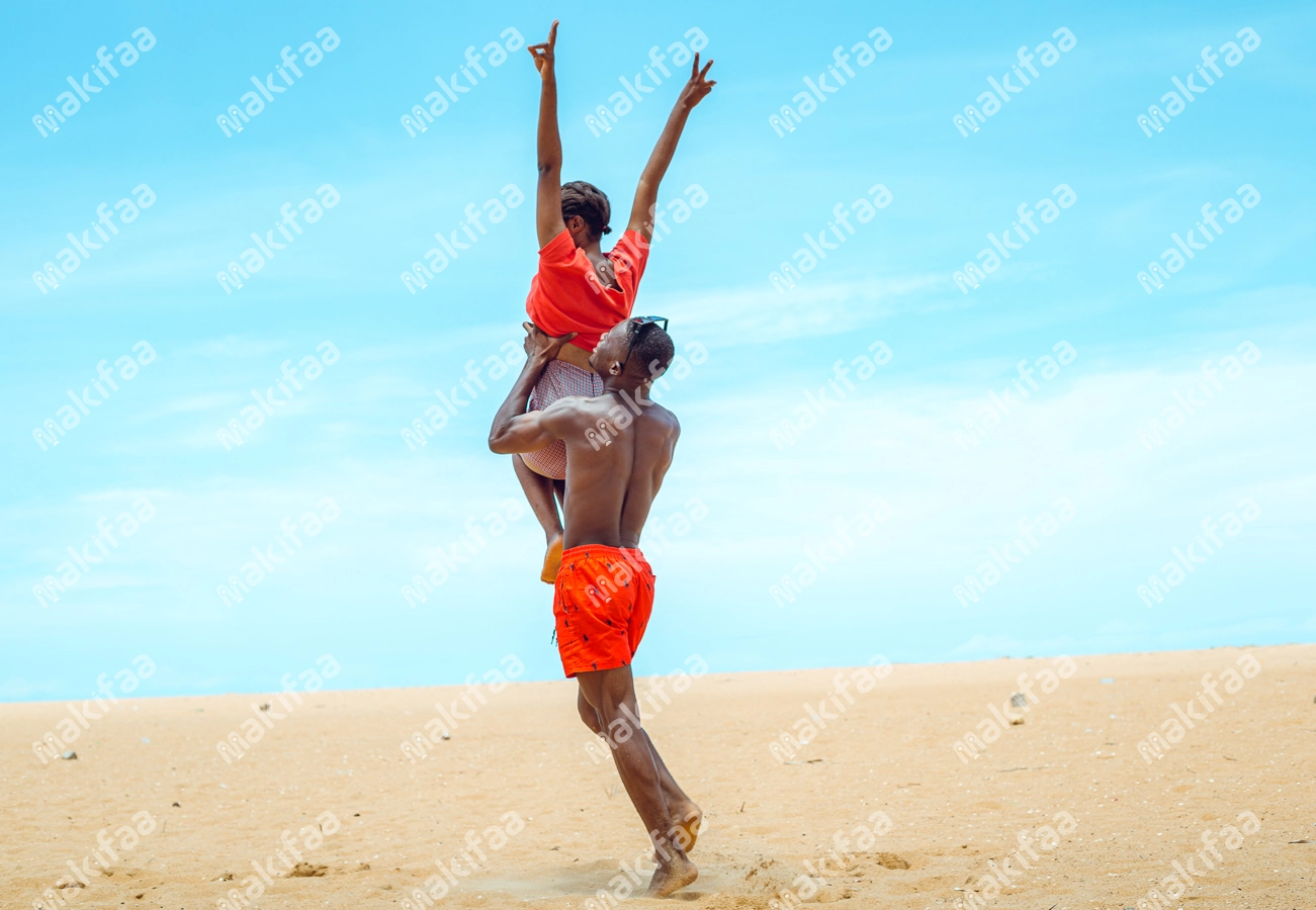 Homme soulevant sa partenaire en bordure de plage