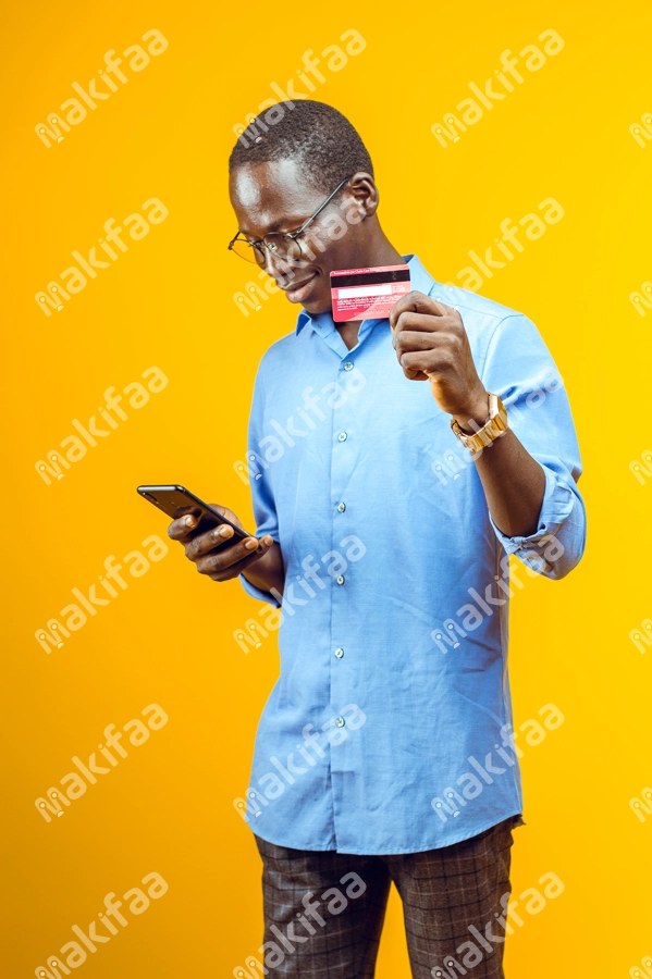 Un beau jeune homme avec une carte bancaire et un téléphone