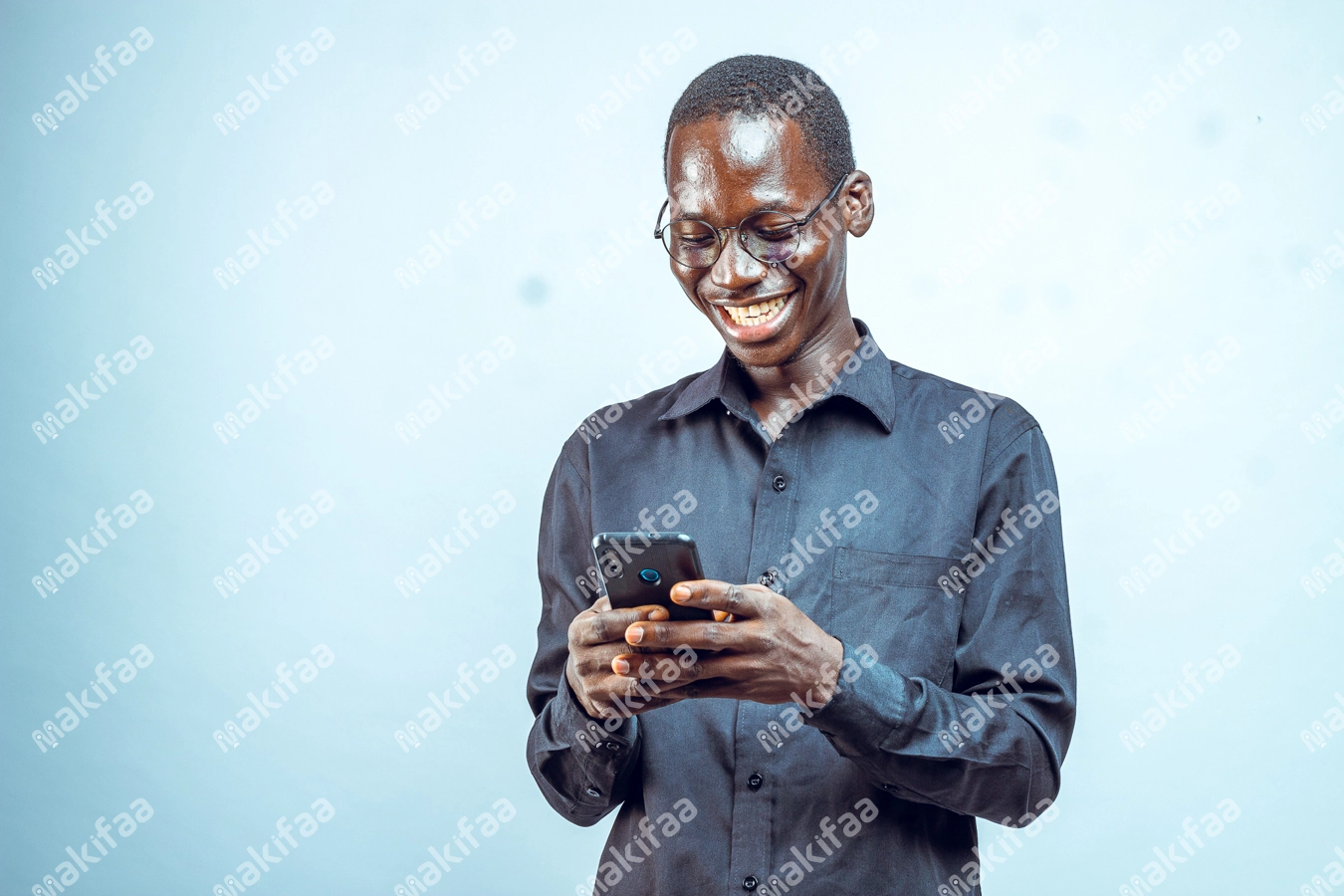 Un jeune homme souriant avec un téléphone et des lunettes