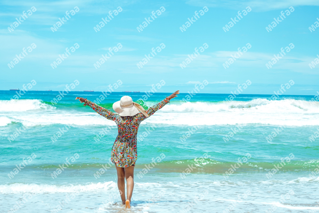 Une femme avec un chapeau et des mains en l'air à la plage