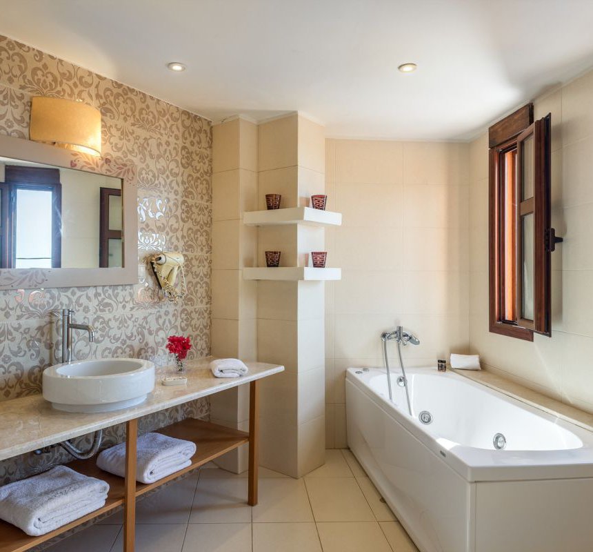 The bathroom of the residence with the sink, the mirror and the towels, the modern walls and the jacuzzi next to the sink