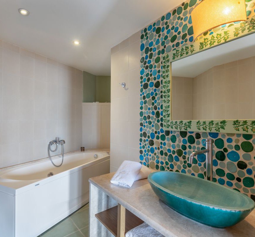 The bathroom of the residence with the sink and mirror, a towel, the spacious jacuzzi and modern lights