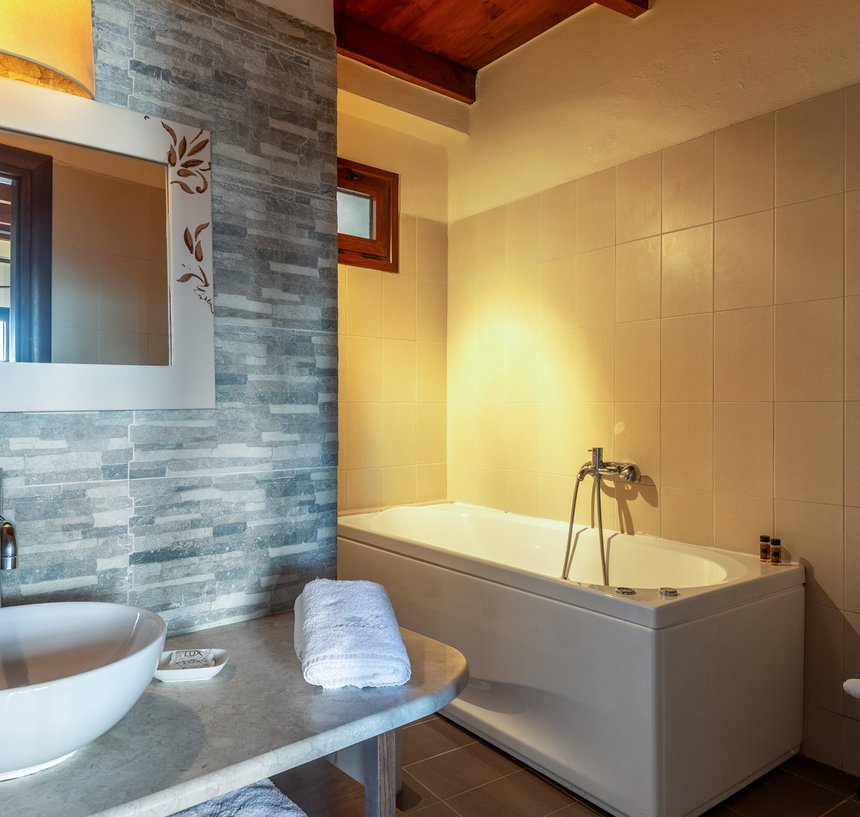 The bathroom of the residence with the sink, the mirror and the towels, the modern walls and the jacuzzi next to the sink