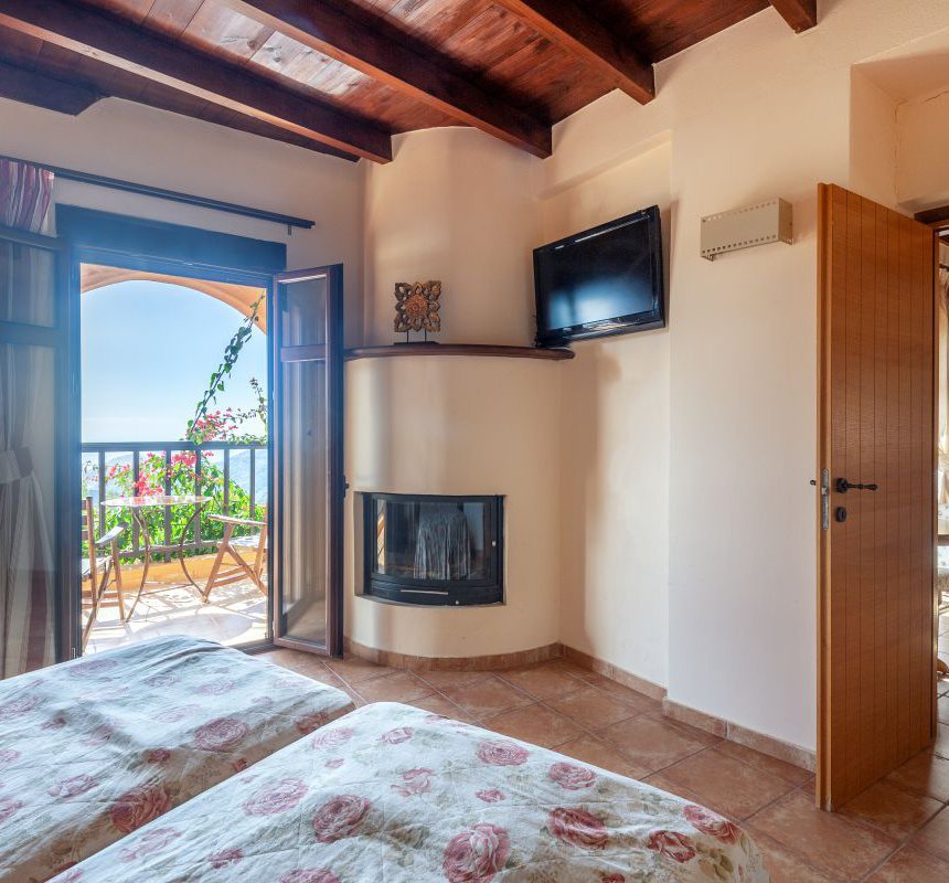 The interior of the maisonette with the two single beds, the fireplace, the TV, the sofa in the maisonette's living room, and the balcony door with the beautiful view