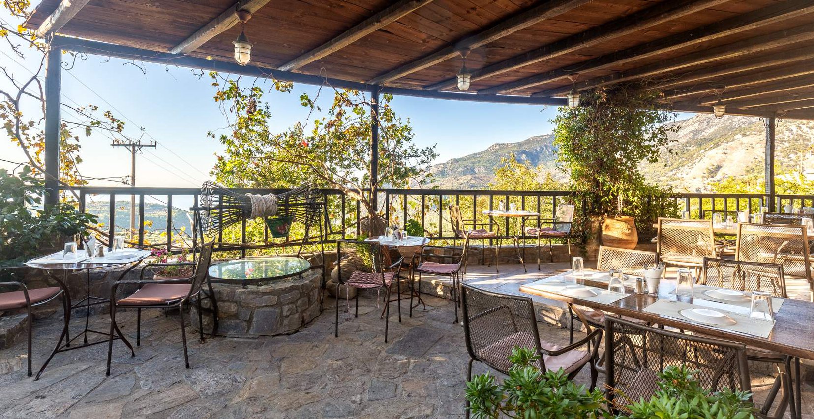 The outdoors restaurant area of the Mala Villa restaurant surrounded by trees, with the tables and chairs