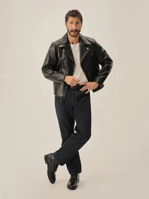 Man wearing black Bruiser moto jacket styled with dark blue jeans and black boots in studio