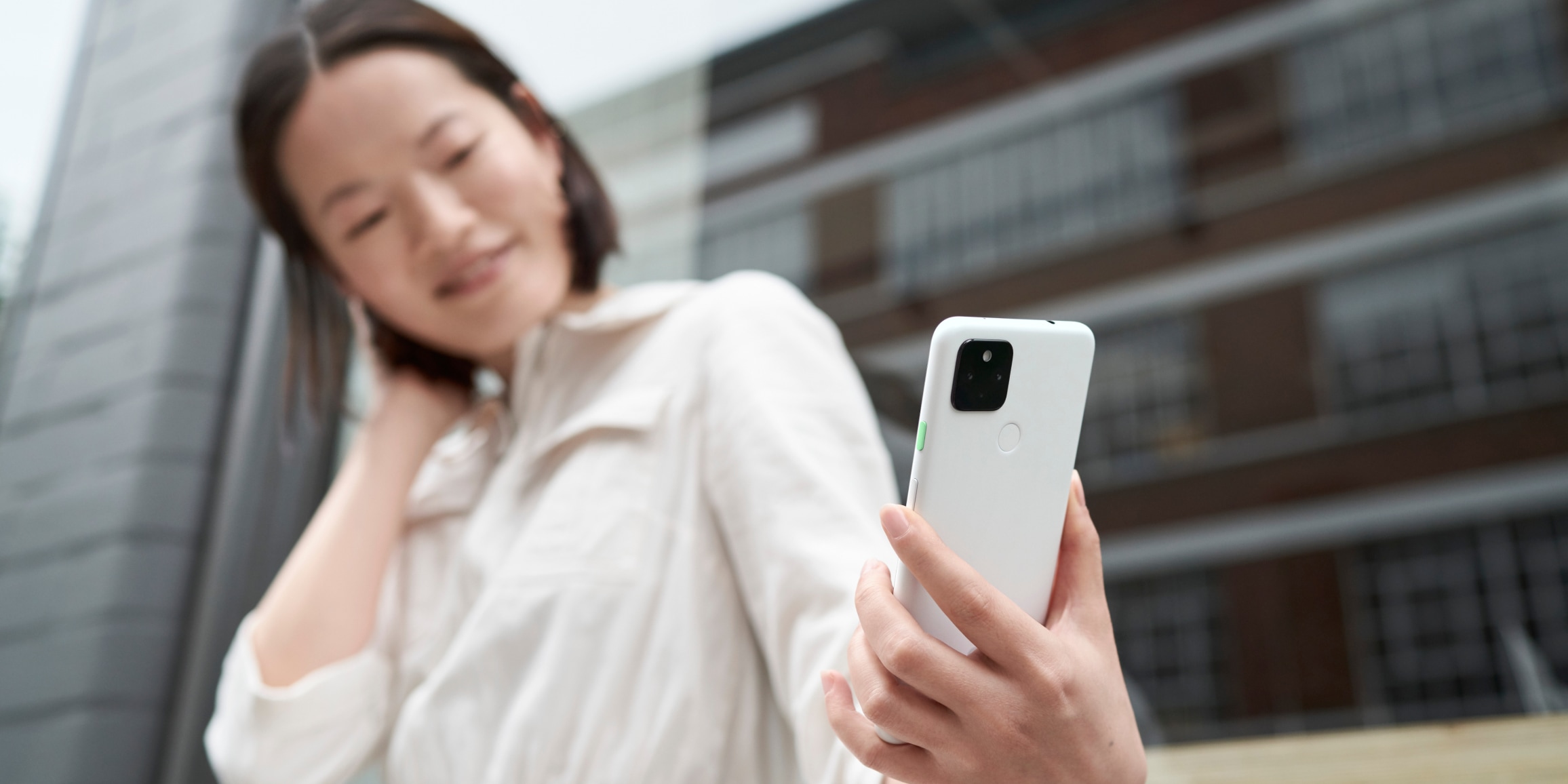 スマートフォンを見つめている白色のシャツを着た女性。