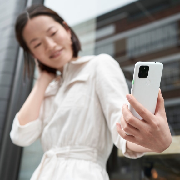 スマートフォンを見つめている白色のシャツを着た女性。