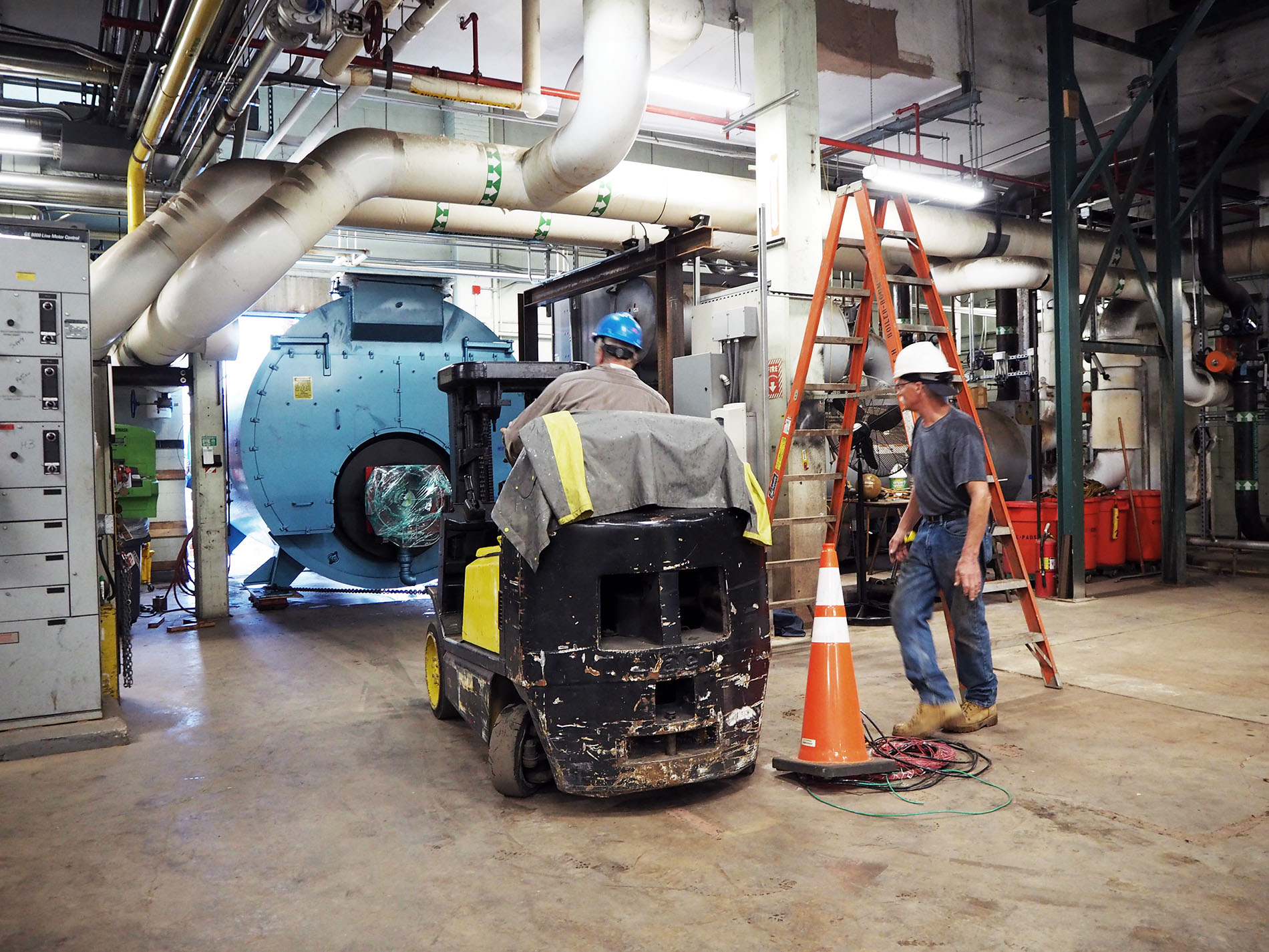 Boiler replacement blog header image two workers on machinery replacing boiler