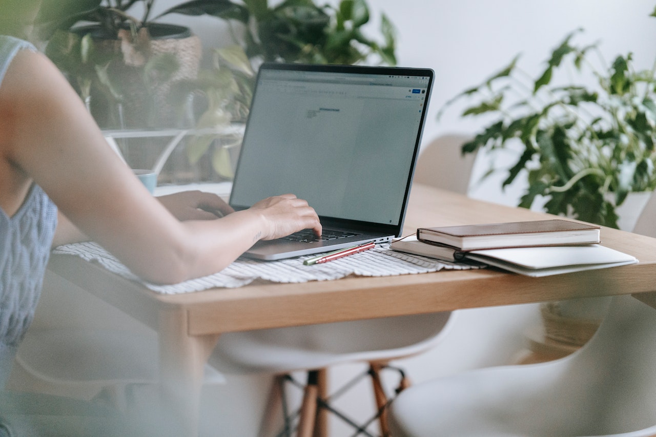 a woman sitting by a desk with a computer on it
