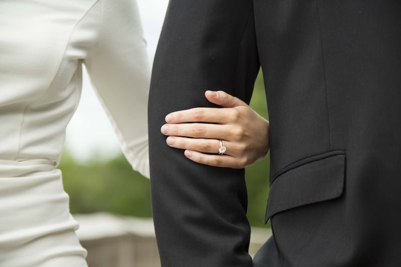 Bride and groom holding hands displaying wedding rings in formal attire