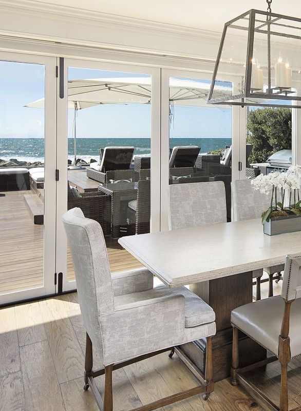 dining table with large glass doors overlooking deck and beach