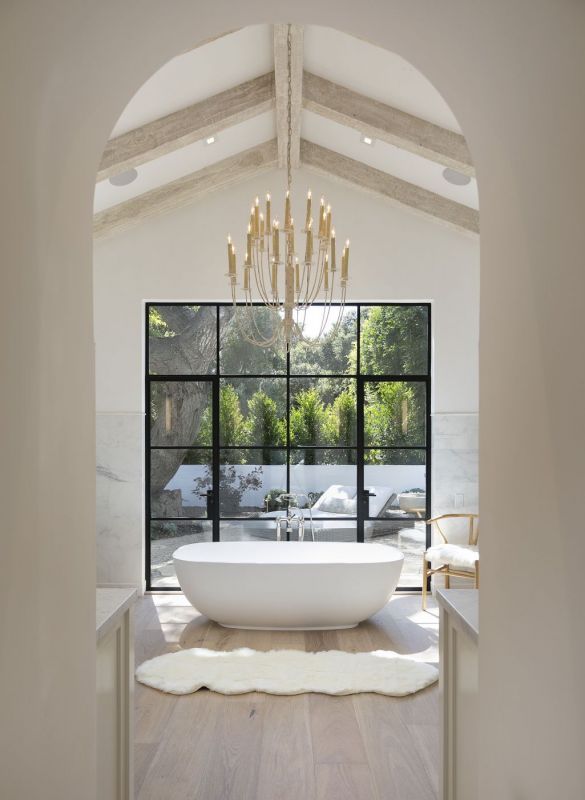 large open bathroom with soaking tub under chandelier in front of large windows