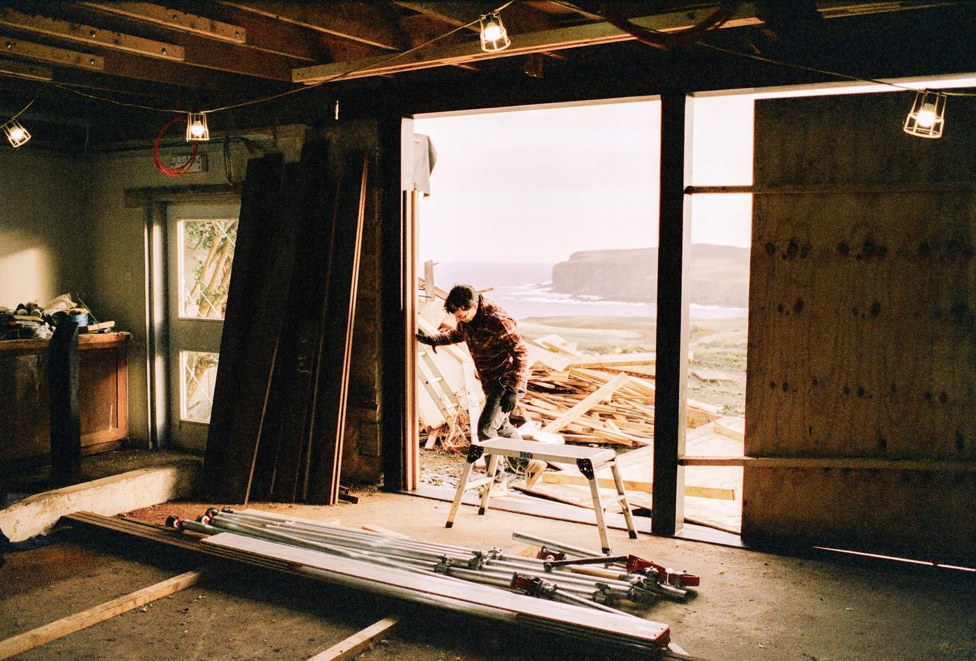 A worker at a tall sea-view doorway during the build