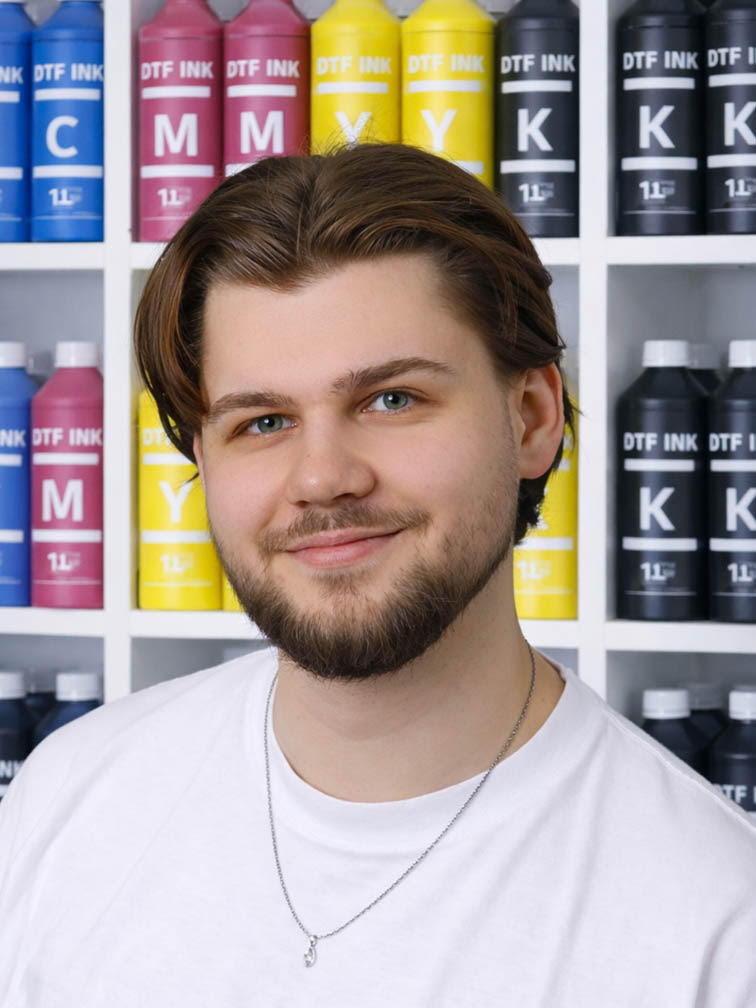 Specjalista produkcji DTF przy regałach z farbami CMYK – kontrola jakości nadruków DTF