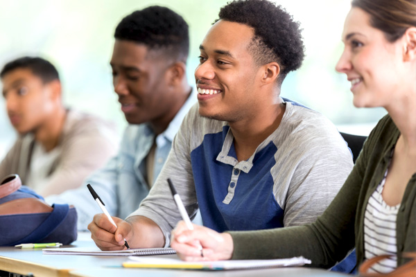 Attentive diverse group of college students take notes during professor's lecture.