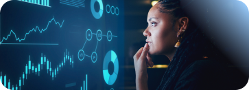 A focused woman with braids studies glowing blue financial charts and data visualizations, representing the data analytics skills gained through IBM.