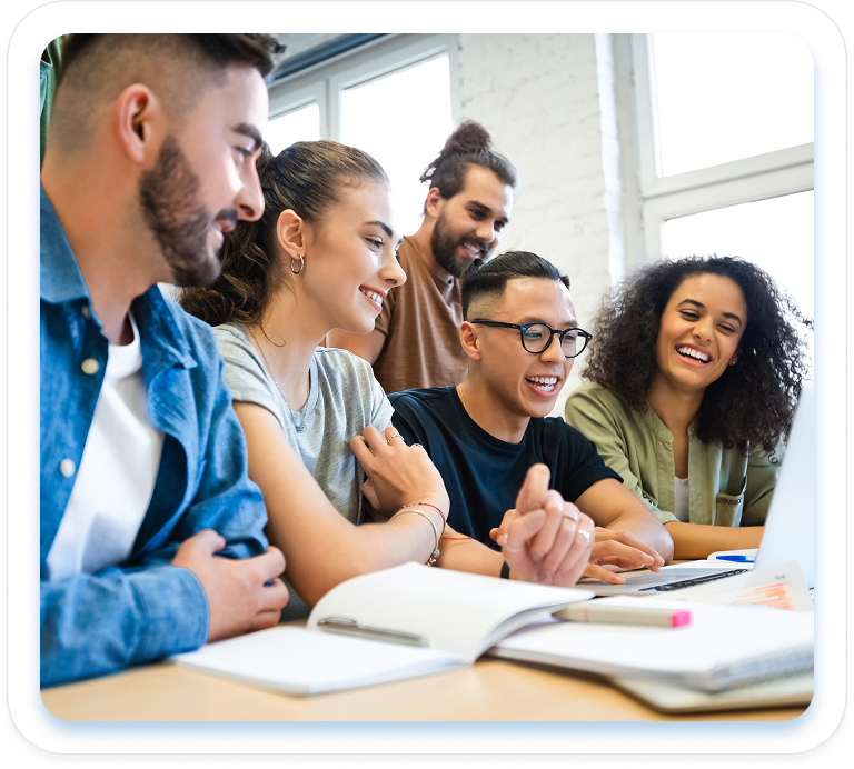 Five diverse, smiling students collaborate on a laptop and notebooks in a bright classroom, embodying the confidence and ease of the English.