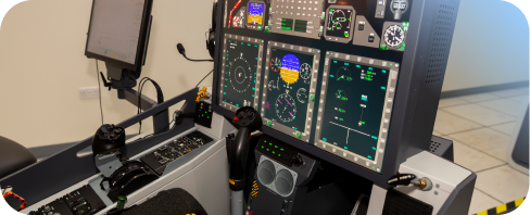 A modern flight simulator setup with illuminated digital instrument panels, dual control yokes, and throttle levers inside a training room.