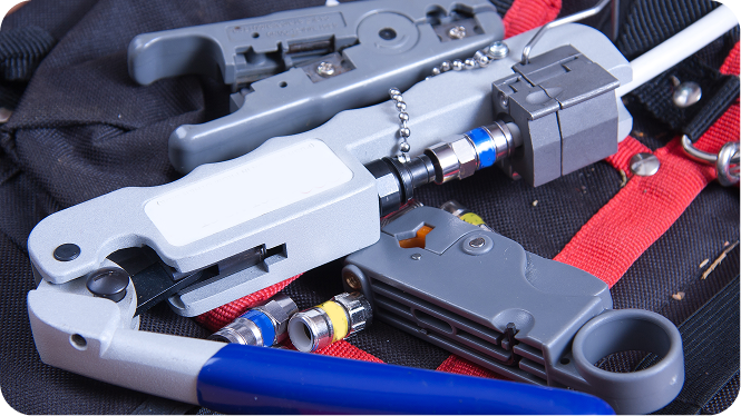 Coaxial cable termination tools, including a compression crimper, rotary cable stripper, and F-connectors on a tool bag