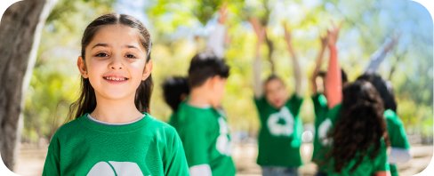 Young girl with a group of other kids with green shirts outside