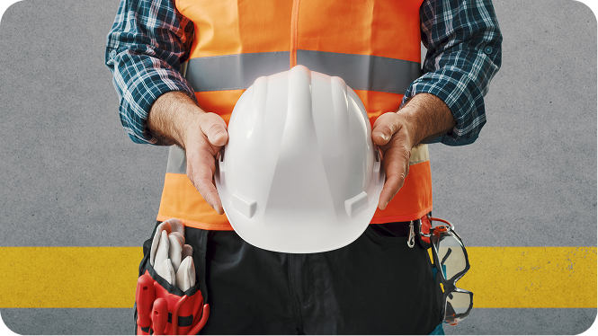 Construction worker holding hard hat in his hands, wearing a orange vest with safety glasses and gloves in his waist.