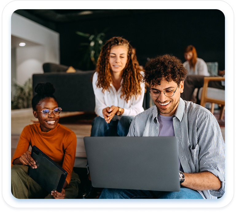 Group of multicultural students smiling while using a laptop in an modern open space office