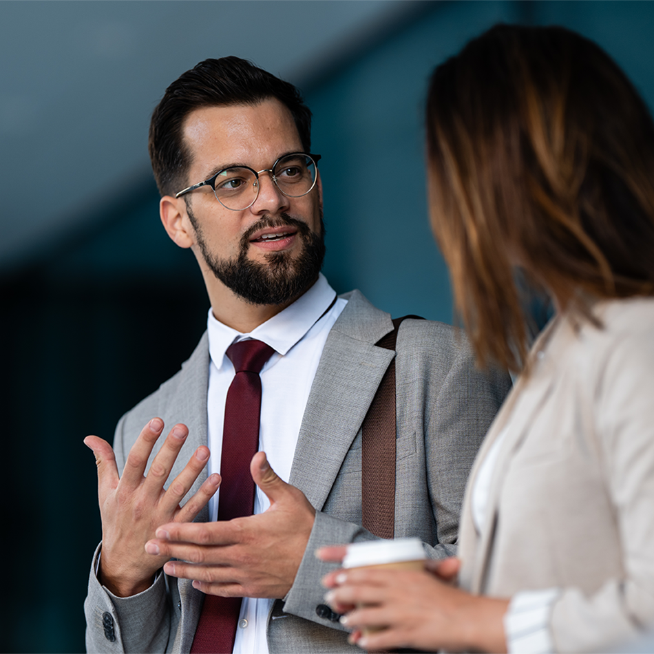 Male accounting or finance professional with glasses and business suit engaged in client consultation or team discussion in corporate office setting
