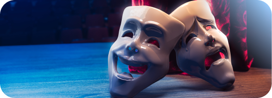 Comedy and tragedy theater masks resting on a stage floor.