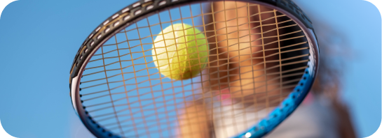 A tennis racket with a yellow tennis ball caught in its strings, against a bright blue sky, suggesting active learning.