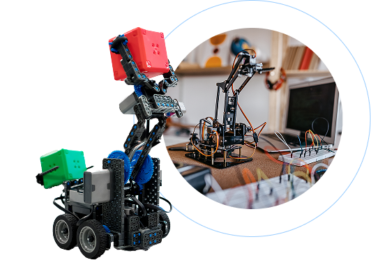 Robotic construction set with multiple modular components in blue, red, and green, showcasing two distinct robotic assemblies. Left side features a mobile wheeled robot base with articulated arm and colored block attachments, built from VEX robotics parts. Right side circular inset displays a more intricate robotic arm mounted on a wooden workbench, with computer and additional electronic components visible in the background. Technical setup suggests educational robotics workshop or engineering design workspace, highlighting precision mechanical engineering and modular construction techniques.