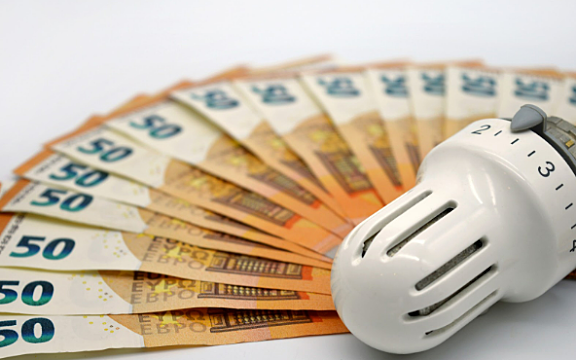 Ein Energieberater kann Ihnen helfen, die Heizlast zu berechnen Geldscheine vor Thermostat-Kopf