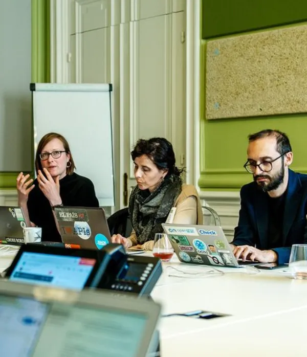 Un grupo de periodistas se sienta alrededor de un escritorio mirando computadoras portátiles