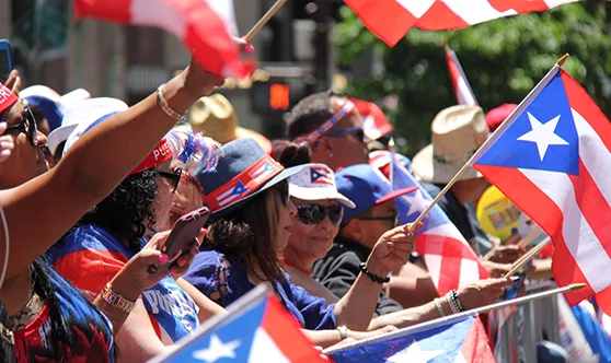 Multitud agitando banderas puertorriqueñas en el desfile por el Día Nacional de Puerto Rico en Nueva York