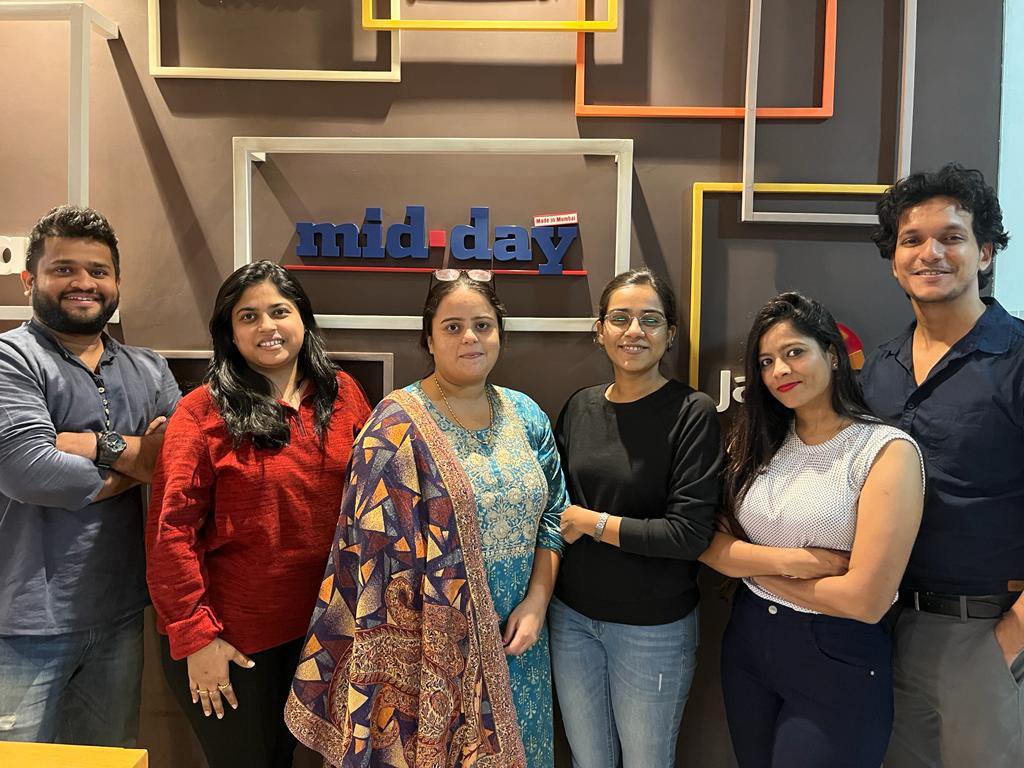 Mid-Day Team in Front of Logo