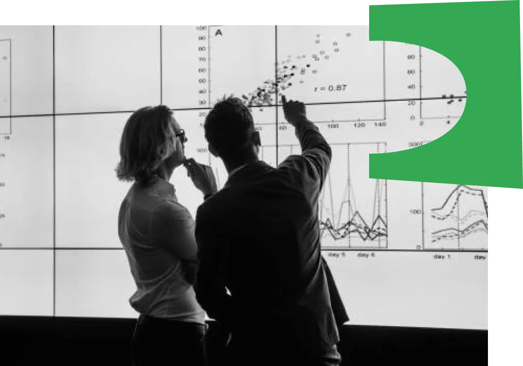 Black and white photo of two people pointing at graphs on a screen