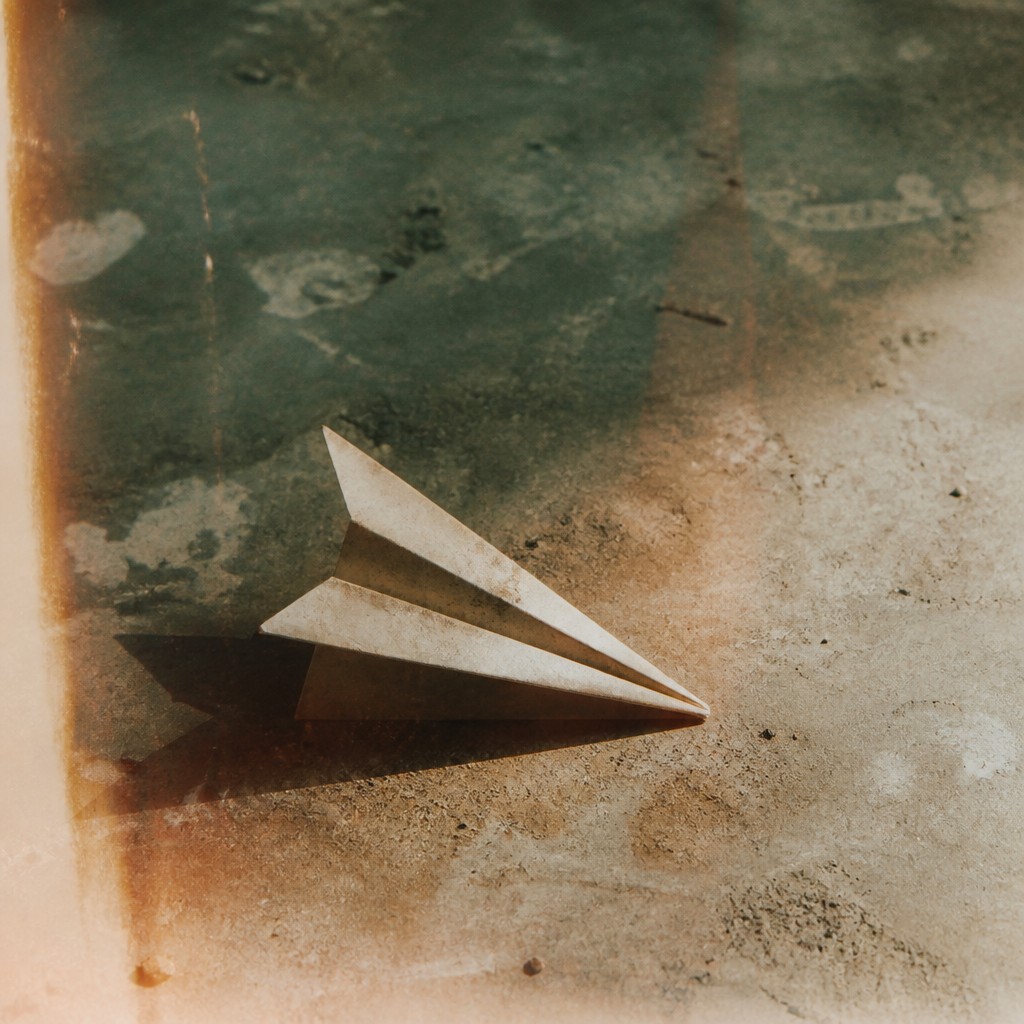 a paper plane, clean minimal composition on a plain background, no text — Land/Environmental Conceptual Art Style icon
