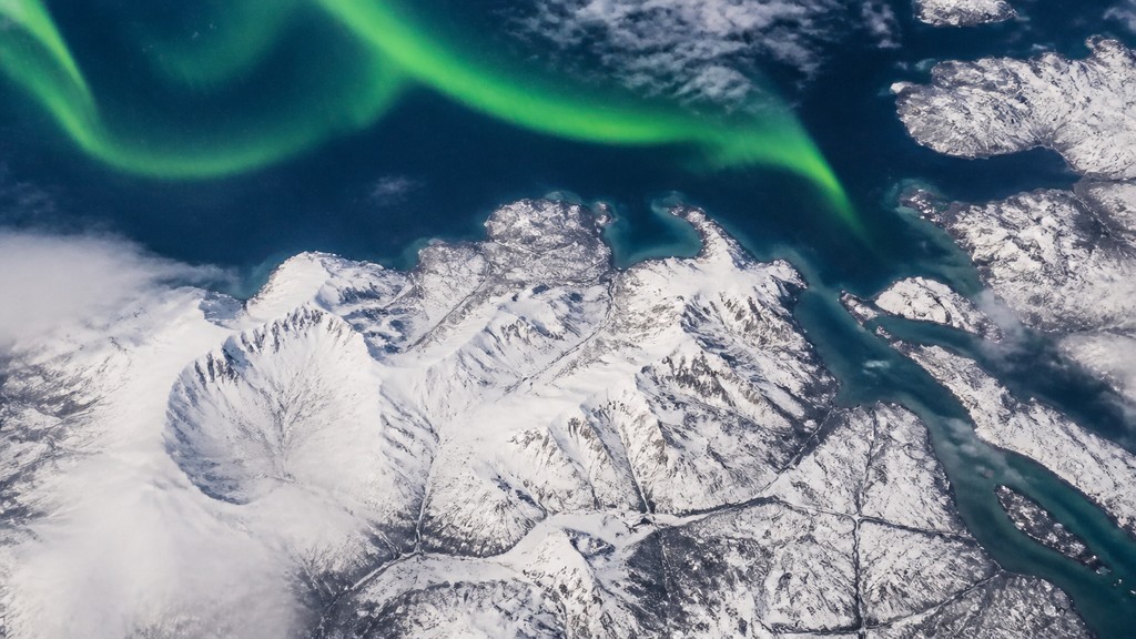 a flowing aurora over snowy peaks, wide sweeping composition, no people, no text — Aerial Drone Photography Style banner
