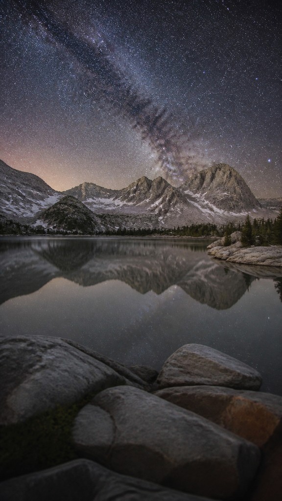 a tranquil mountain lake beneath a starry night sky, no people, no text — Photographic Realism Art Style phone wallpaper