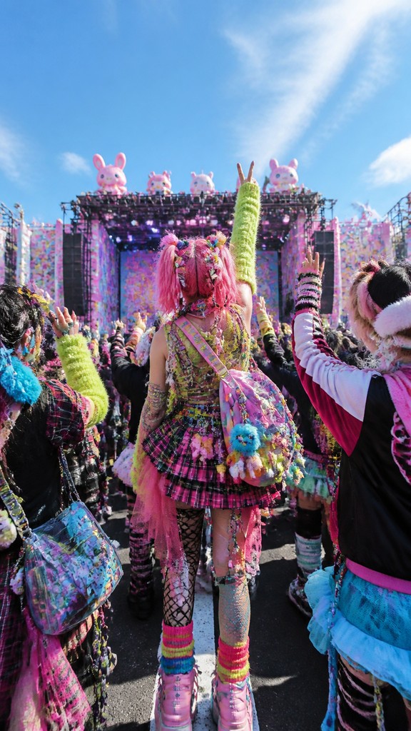 a live music scene with a glowing stage and silhouetted crowd, energetic vertical composition with open space at the top, no text — Harajuku Fashion Style flyer